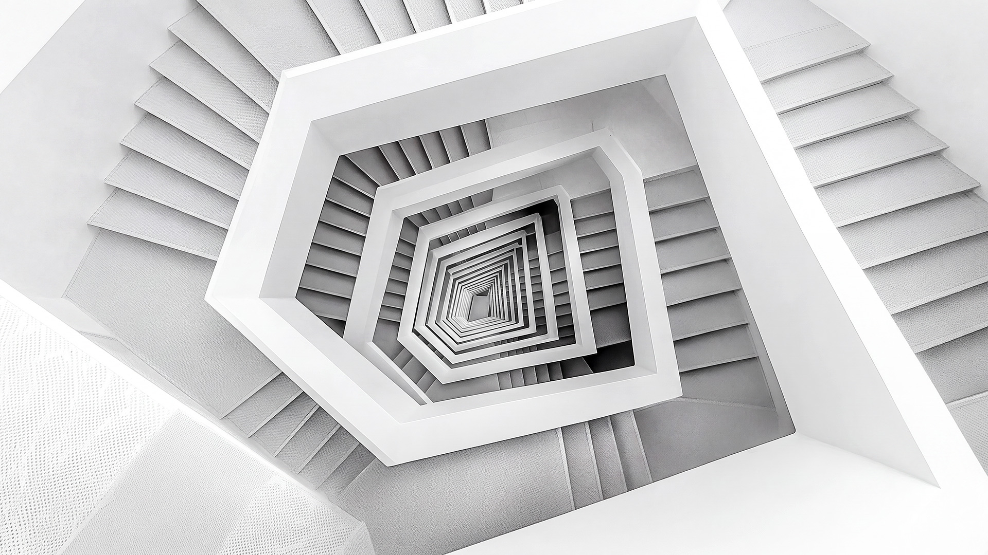 A monochrome architectural staircase converging toward a central point, representing the disciplined structure behind executive decisions.